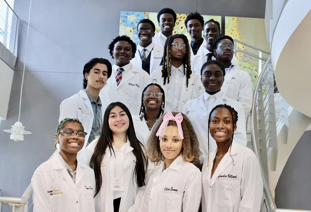 A group of students in white lab coats as part of Georgia Tech’s Project ENGAGES, a high school science education program that works with seven minority-serving public high schools in Atlanta to bring underrepresented groups into STEM fields.