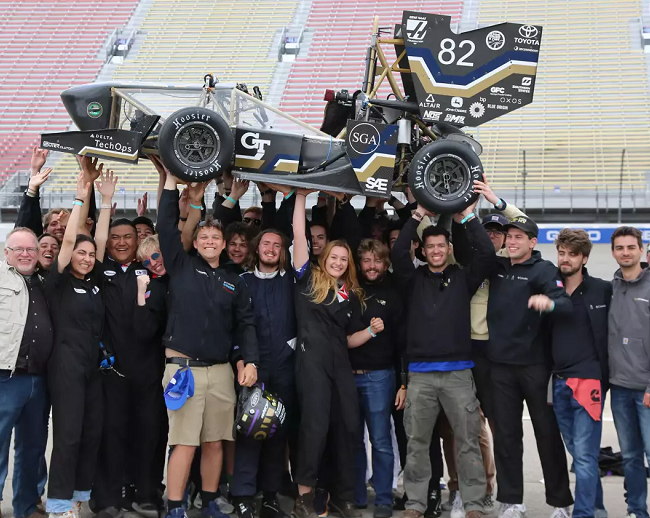 students holding race car above their heads
