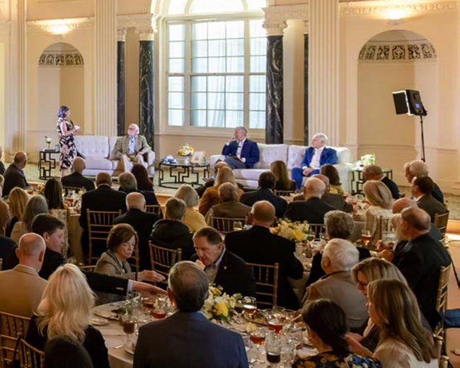 photo from Hill Society event, full room with fancy tables, people gathered eating, panel discussion